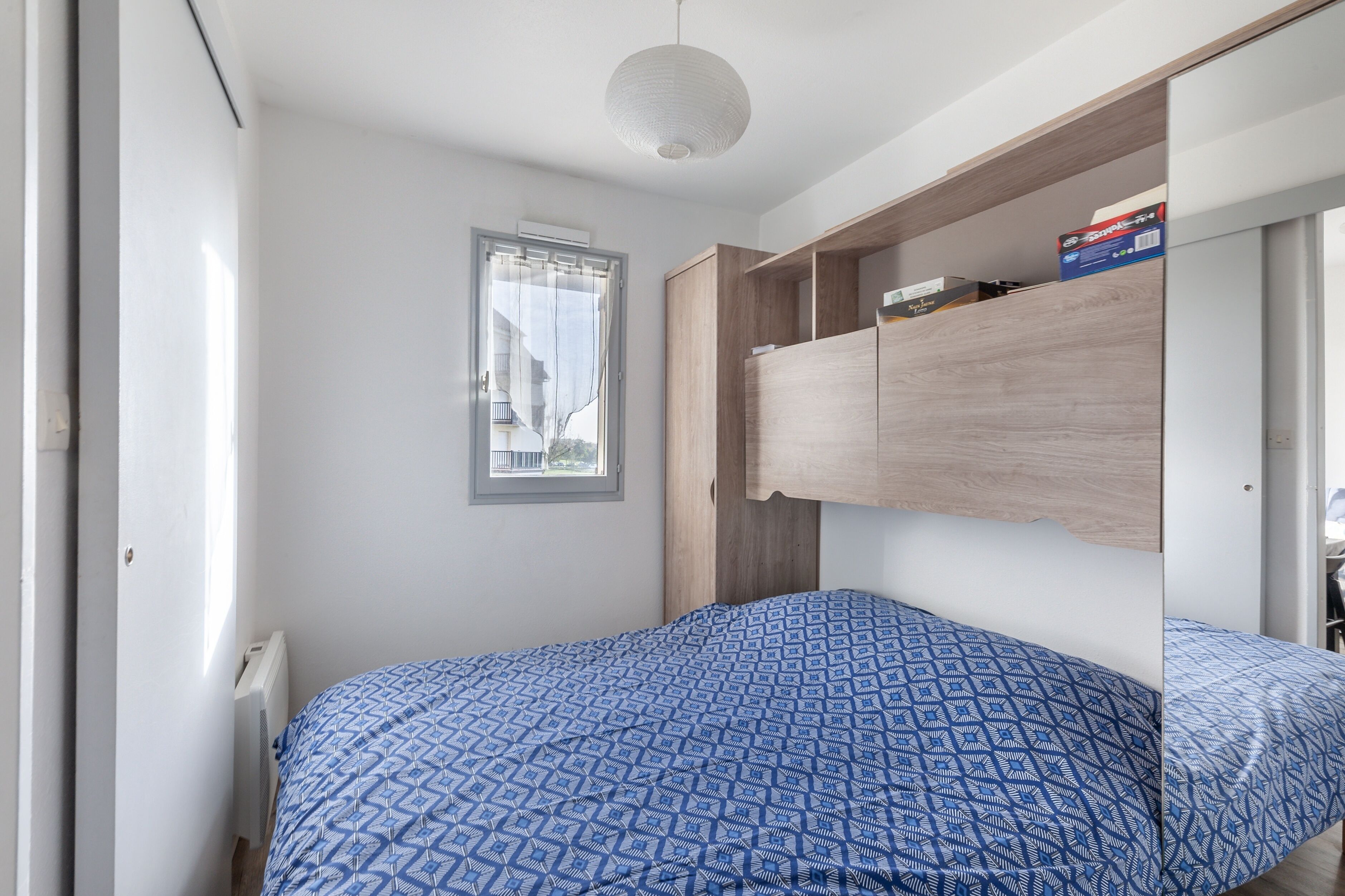 A bedroom with a bed, a window, and a built-in wardrobe.
