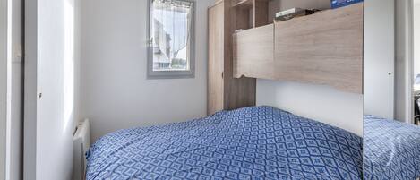 A bedroom with a bed, a window, and a built-in wardrobe.