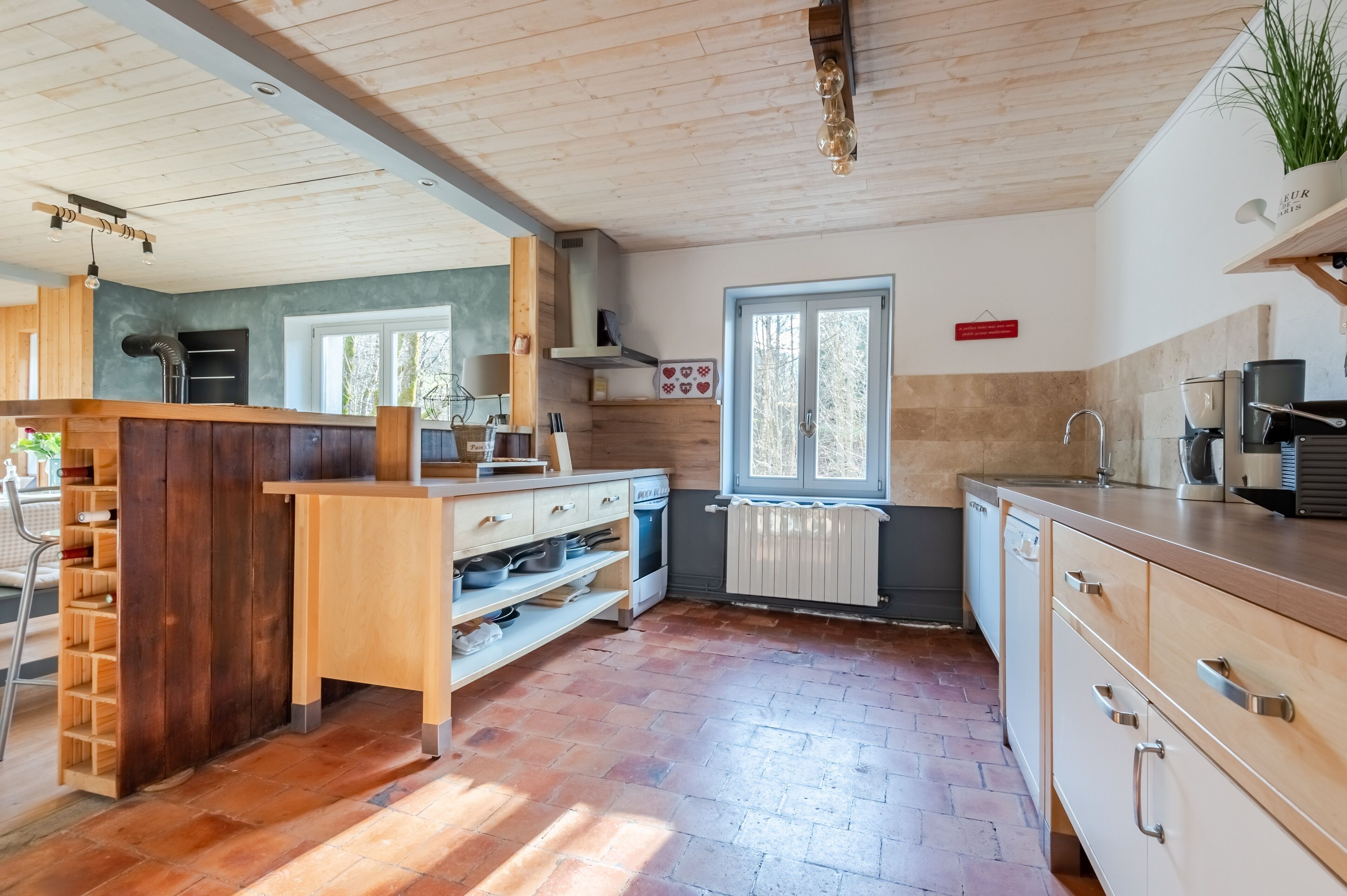 A modern kitchen with wooden cabinets, a built-in island, and a window providing natural light.