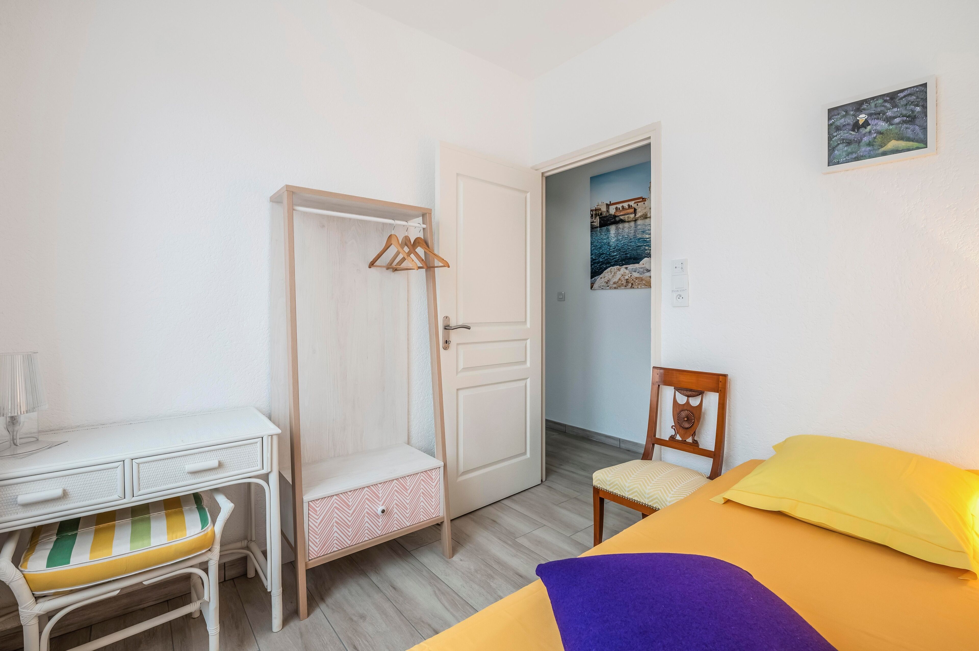Ein Schlafzimmer mit einem Bett, einem Schreibtisch mit Stuhl, einem Kleiderschrank und einer Tür zu einem anderen Raum.
