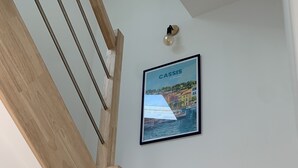 A wooden staircase with a framed picture of Cassis on the wall. - Duplex apartment in the heart of Cassis village (Cassis)
