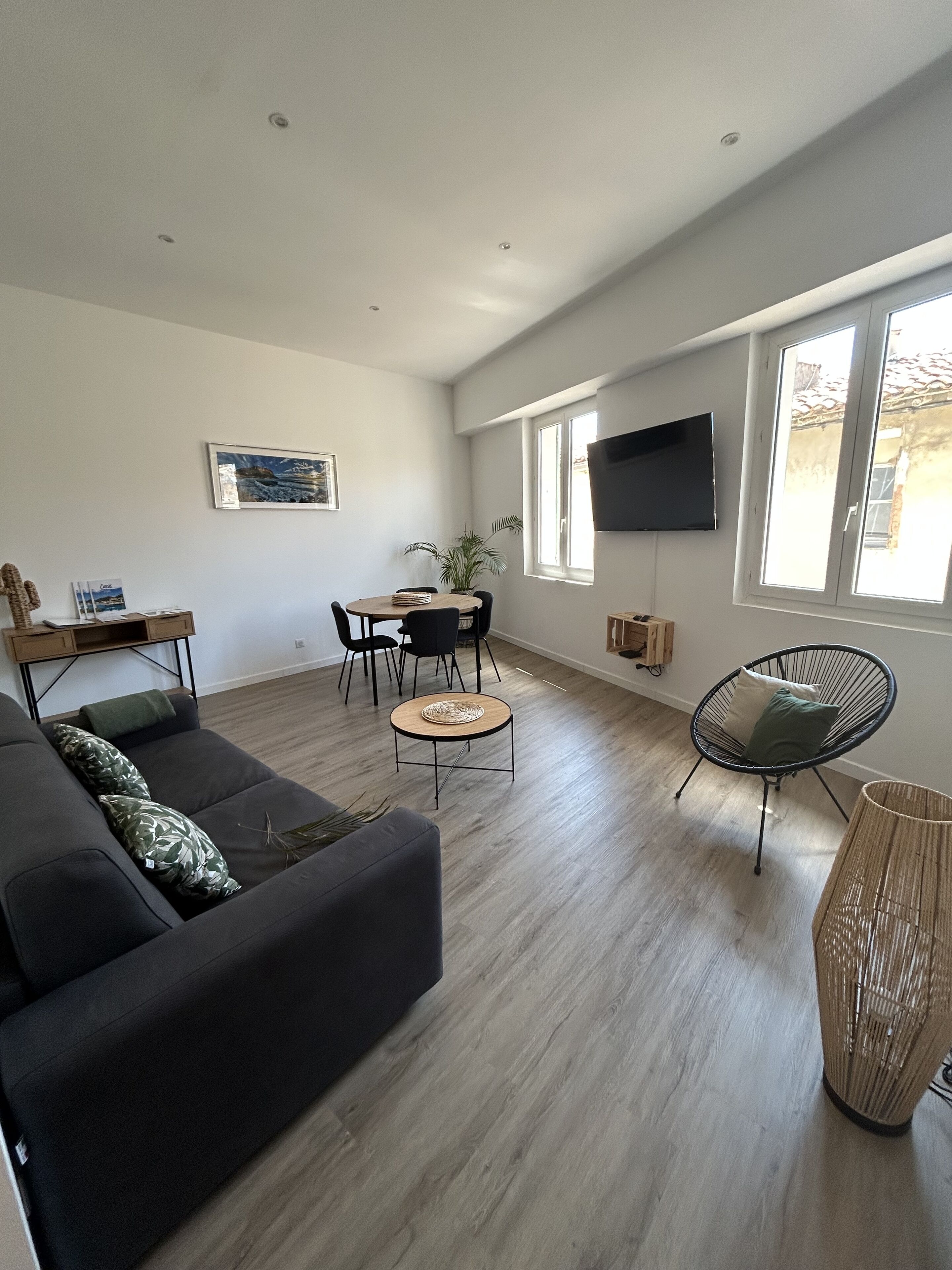 A modern living room with a dark-colored sofa, a round coffee table, a black chair, and a TV mounted on the wall.