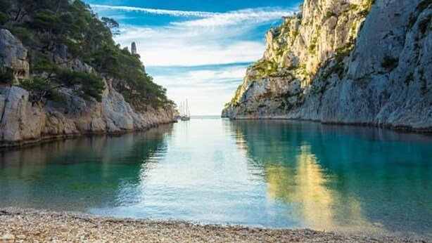 A coastal scene with a calm body of water, rocky cliffs, and sparse vegetation. - Duplex apartment in the heart of Cassis village (Cassis)