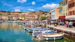 A harbor with boats docked along the waterfront, surrounded by colorful buildings and a clear blue sky. - Duplex apartment in the heart of Cassis village (Cassis)