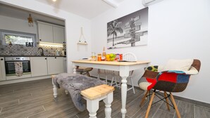 A modern kitchen with white cabinets, a wooden bench, and a dining table with chairs. - Casa Ambi (Trogir)