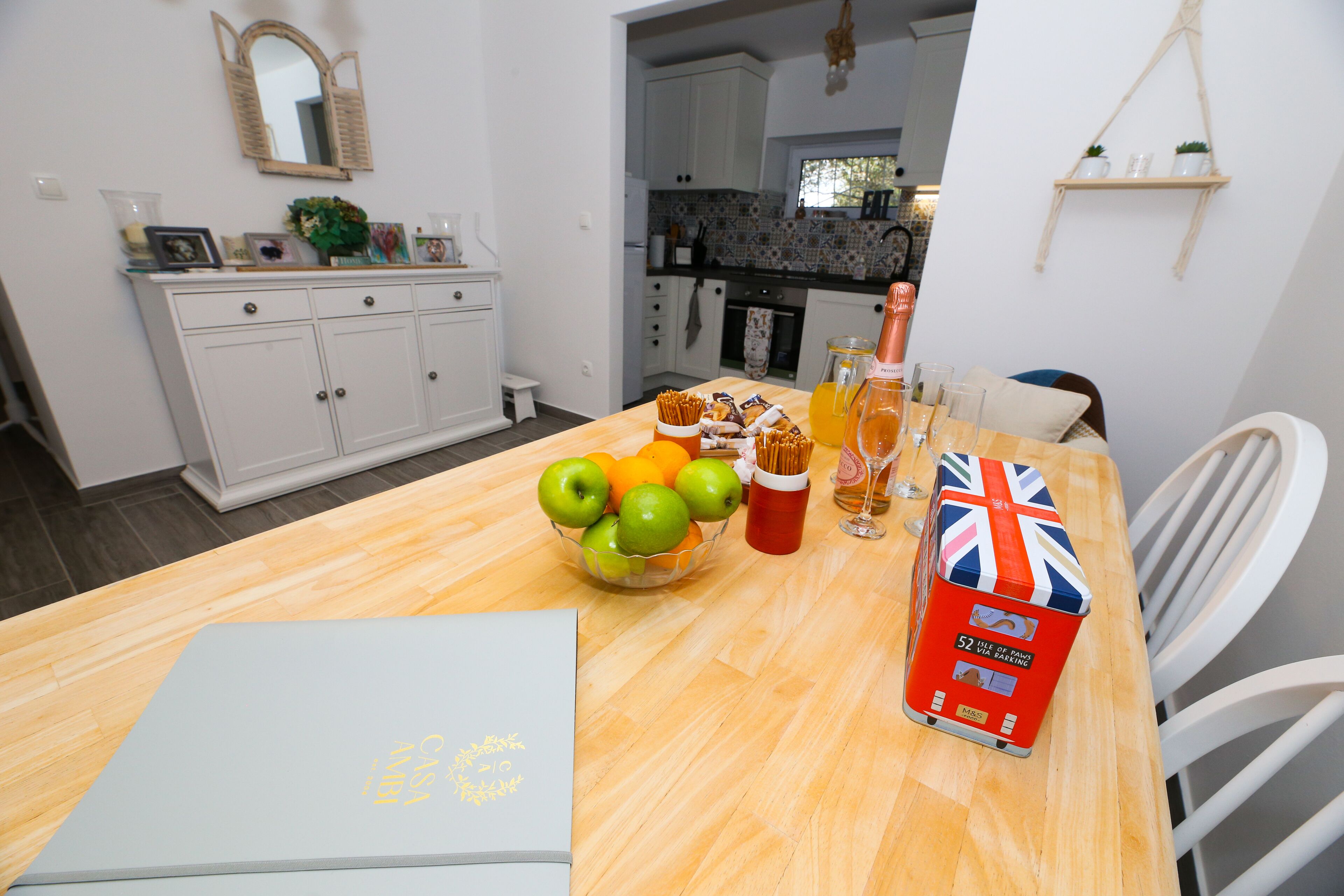 A dining table with a laptop, a bowl of fruit, a juice pitcher, and a box of tissues.