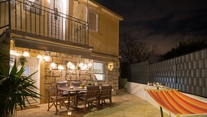 A patio with a dining table and chairs, a hammock, and a stone wall. - Casa Ambi (Trogir)