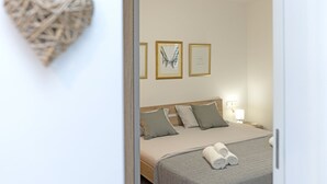 A hotel room with a bed, pillows, a bedside table with a lamp, and framed artwork on the wall. - Casa Ambi (Trogir)