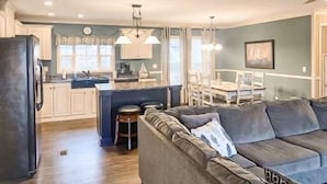 Une cuisine moderne avec des meubles blancs, un îlot central et des luminaires suspendus.