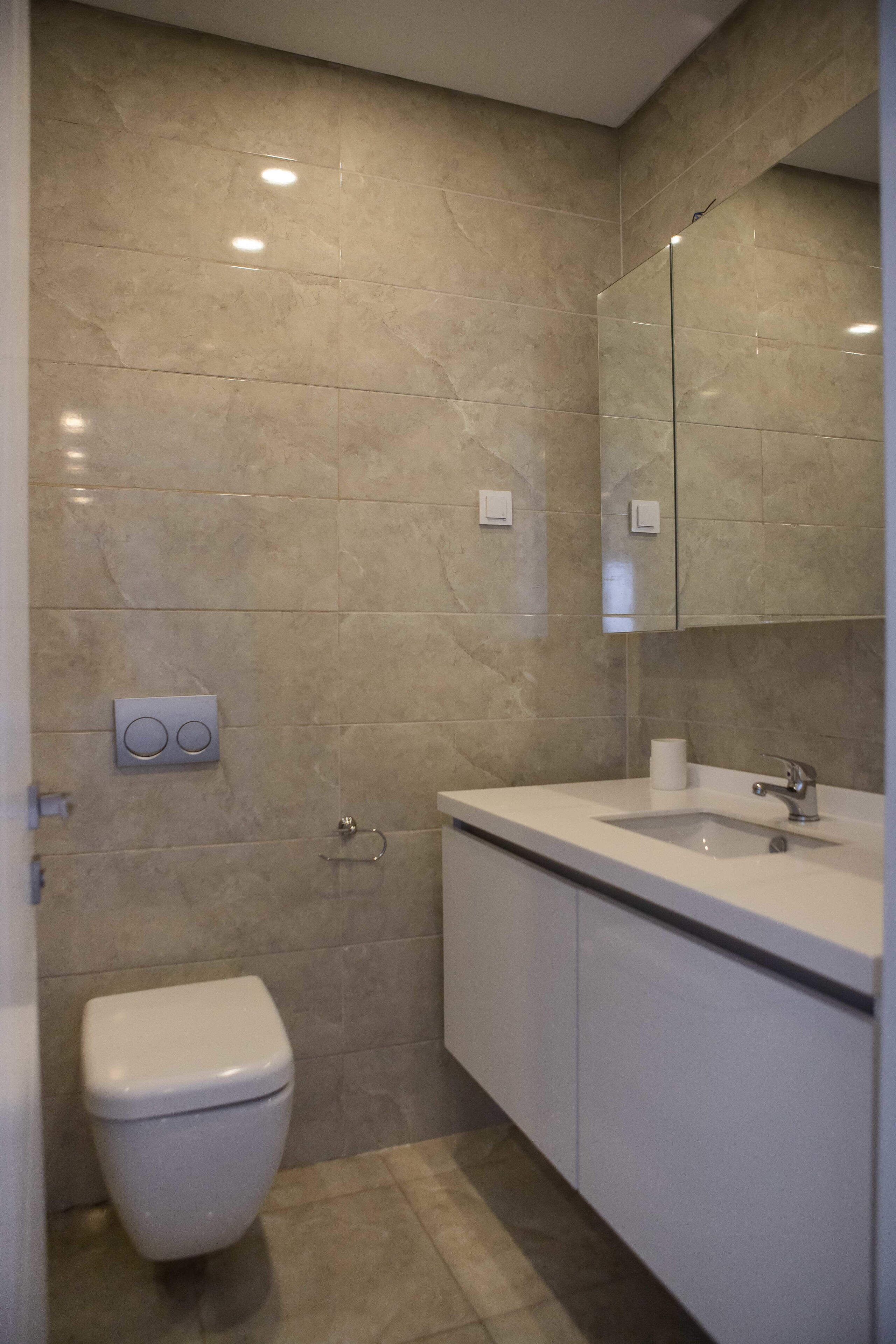 Une salle de bain moderne avec des toilettes, un lavabo et un miroir.