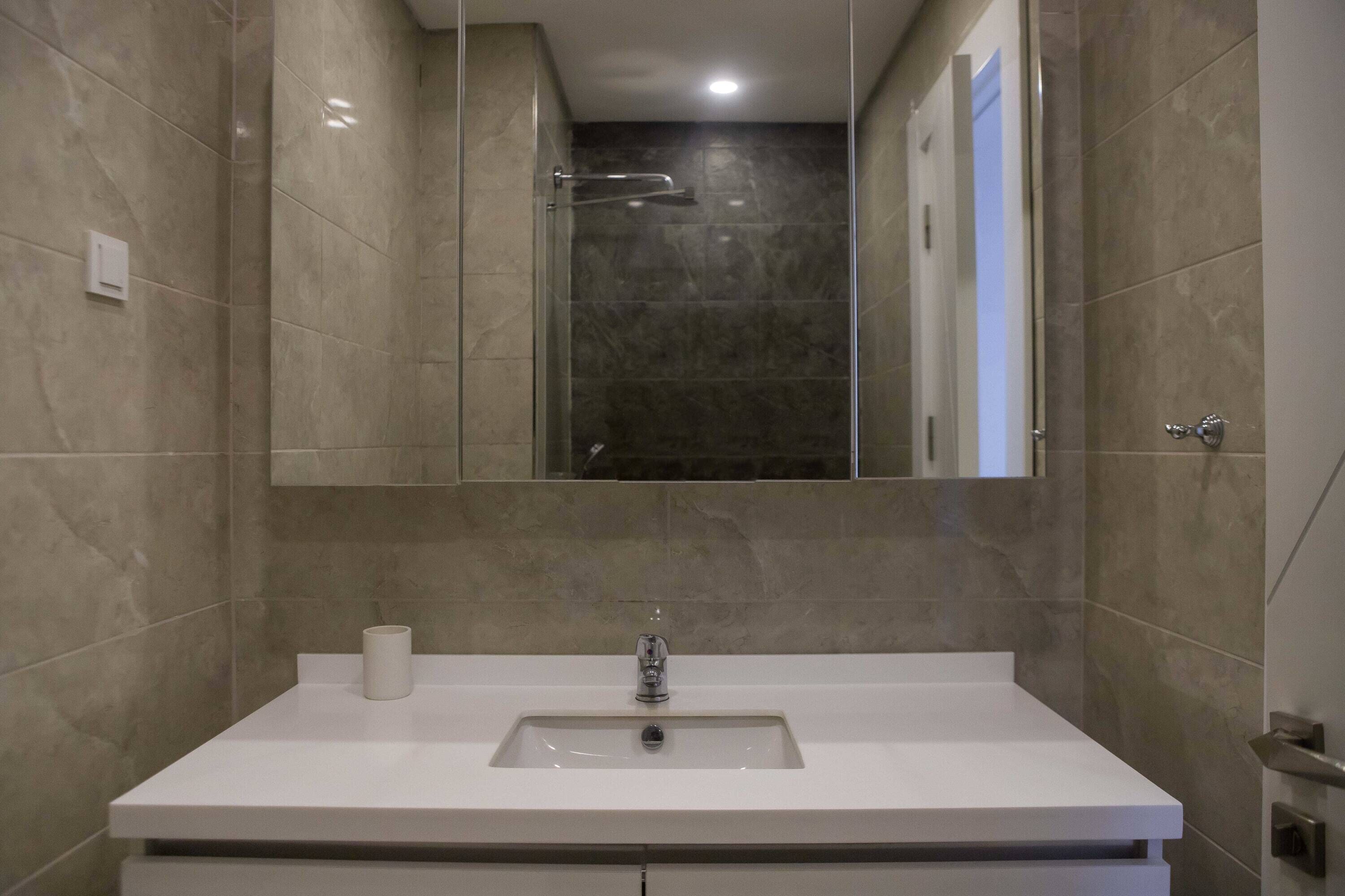 Une salle de bain avec un lavabo blanc, un miroir et une douche.