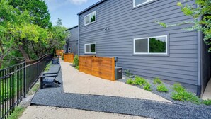 A modern two-story house with a gravel driveway, wooden fence, and a black metal railing. - Prime SoCo cute studio w/ laundryWiFi, 7 Min to DT (Austin)