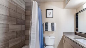 Een moderne badkamer met douche, toilet en wastafel.