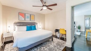 Een moderne slaapkamer met een groot bed, een plafondventilator en kunst aan de muur.