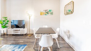 A modern living room with a flat-screen TV, white furniture, and artwork on the walls. - Comfy 2BR king suite, fast WiFi, 8 min to Downtown (Austin)