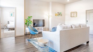 A modern living room with a sofa, TV, ceiling fan, and decorative plants. - Comfy 2BR king suite, fast WiFi, 8 min to Downtown (Austin)