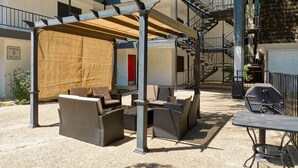 An outdoor patio area with wicker furniture, a covered seating area, and a barbecue grill. - Prime SoCo cozy 1BR king suite w/ pool, parking (Austin)