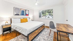 A bedroom with a bed, bedside table, chair, and a small wooden table. - Prime SoCo cozy 1BR king suite w/ pool, parking (Austin)