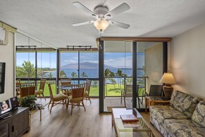 A spacious living area with a balcony overlooking a scenic view of the ocean and mountains. - Kihei Surfside, #608 1 Bedroom Condo by RedAwning (Kihei)
