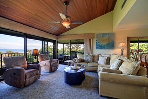 A spacious living room with a ceiling fan, large windows, and a view of the outdoors. - Wailea Elua, #0106 1 Bedroom Condo by RedAwning (Kihei)