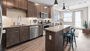 A modern kitchen with dark wood cabinets, stainless steel appliances, and a central island with bar stools.