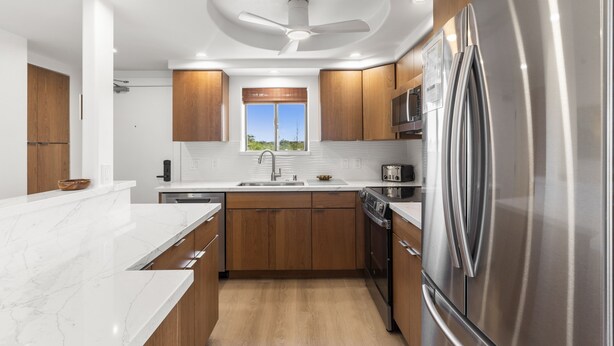 A modern kitchen with wooden cabinets, a stainless steel refrigerator, and a built-in oven. - Kihei Beach, #510 2 Bedroom Condo by RedAwning (Kihei)