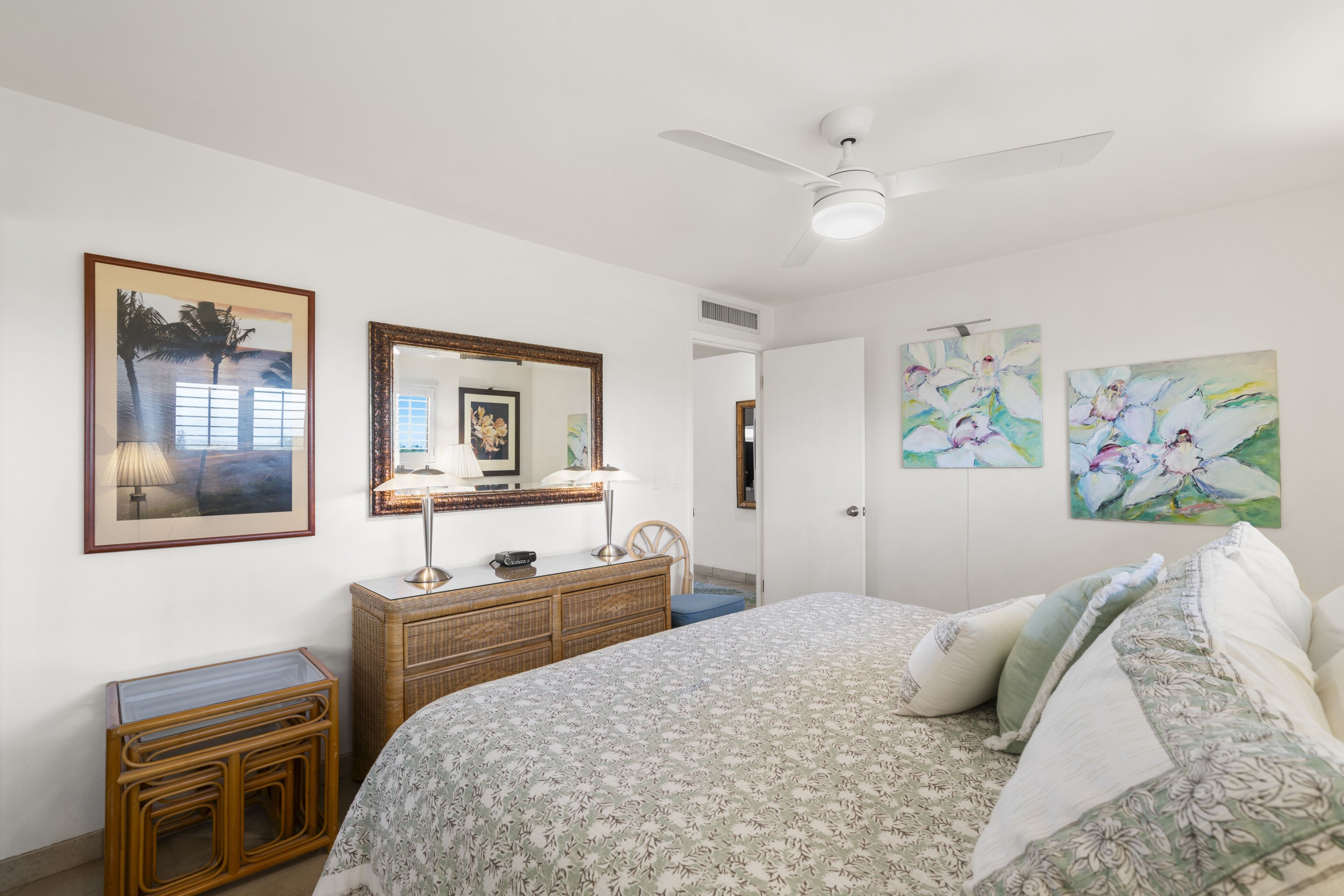 Un dormitorio con cama, cómoda, espejo y obras de arte en las paredes.