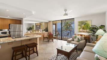 Una cocina moderna con una isla grande, taburetes de bar y un comedor con vista al océano.