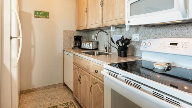 A compact kitchen with a refrigerator, microwave, stove, and coffee maker. - Sugar Beach Resort, #319 1 Bedroom Condo by RedAwning (Kihei)