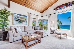 A modern living room with a sectional sofa, a glass coffee table, and a view of the ocean. - Wailea Elua, #1402^ 1 Bedroom Condo by RedAwning (Kihei)