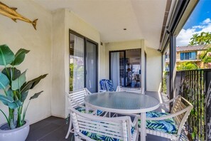 A balcony with a round glass table and white wicker chairs, a potted plant, and a fish decoration on the wall. - Wailea Elua, #1402^ 1 Bedroom Condo by RedAwning (Kihei)