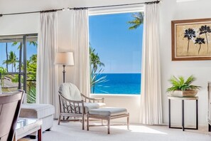 Una habitación con vista al océano, una silla, una mesa y una lámpara.