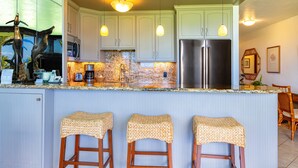 Una cucina con isola centrale, elettrodomestici in acciaio inossidabile e una scultura decorativa a forma di pesce.