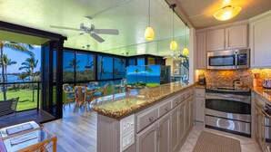 Una cucina moderna con un'isola grande, elettrodomestici in acciaio inossidabile e vista sull'oceano.
