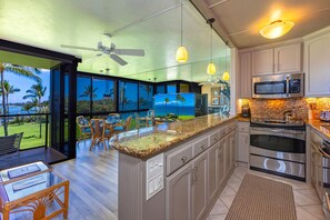 A modern kitchen with a large island, stainless steel appliances, and a view of the ocean.