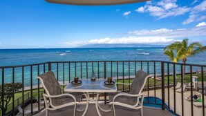 Ein Balkon mit Tisch und Stühlen mit Blick auf einen Strand und einen klaren Meerblick sowie Palmen.
