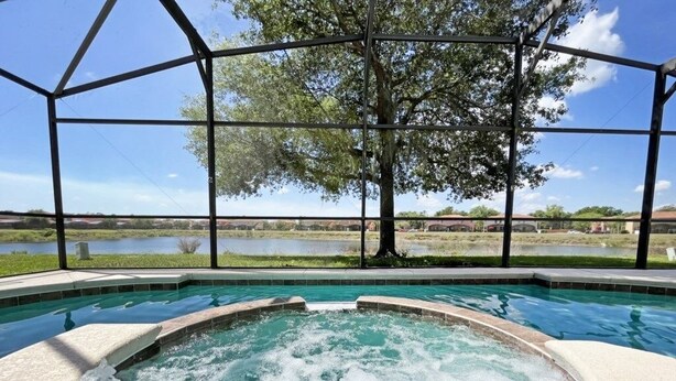 A hot tub with a view of a lake and trees, enclosed by a metal structure. - Villa Marcello 4 Bedroom Home by RedAwning (Kissimmee)