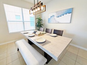 Een eethoek met een lange tafel, banken en een hanglamp.