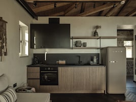 A compact kitchen with a built-in oven, a refrigerator, and a wooden countertop.