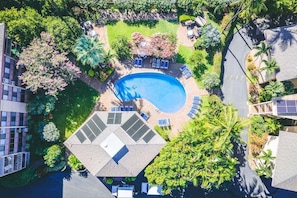 Oversigtsbillede af et boligområde med swimmingpool, liggestole og grøn bevoksning omkring.