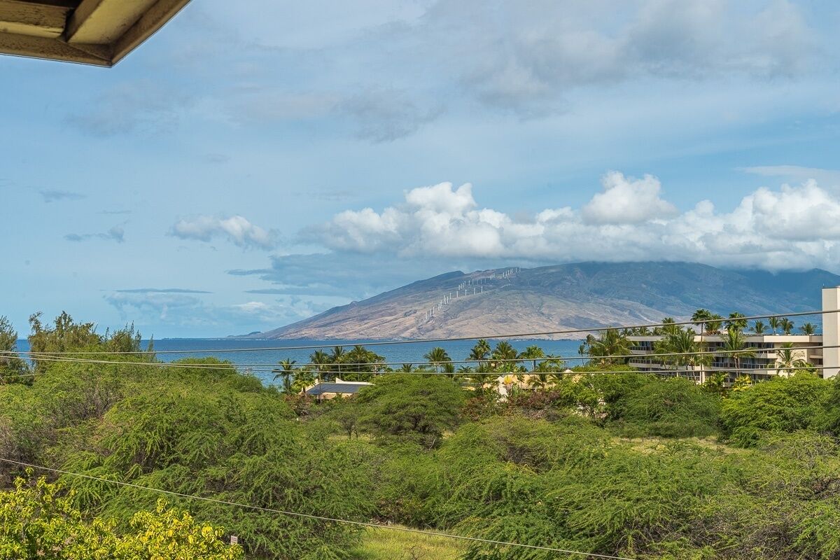 Paisaje montañoso con vista a un cuerpo de agua y un edificio de varios pisos.