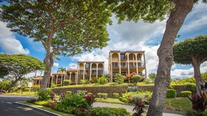 A hotel with a symmetrical facade, multiple balconies, and lush landscaping. - Maui Hill by Coldwell Banker Island Vacations (Kihei)