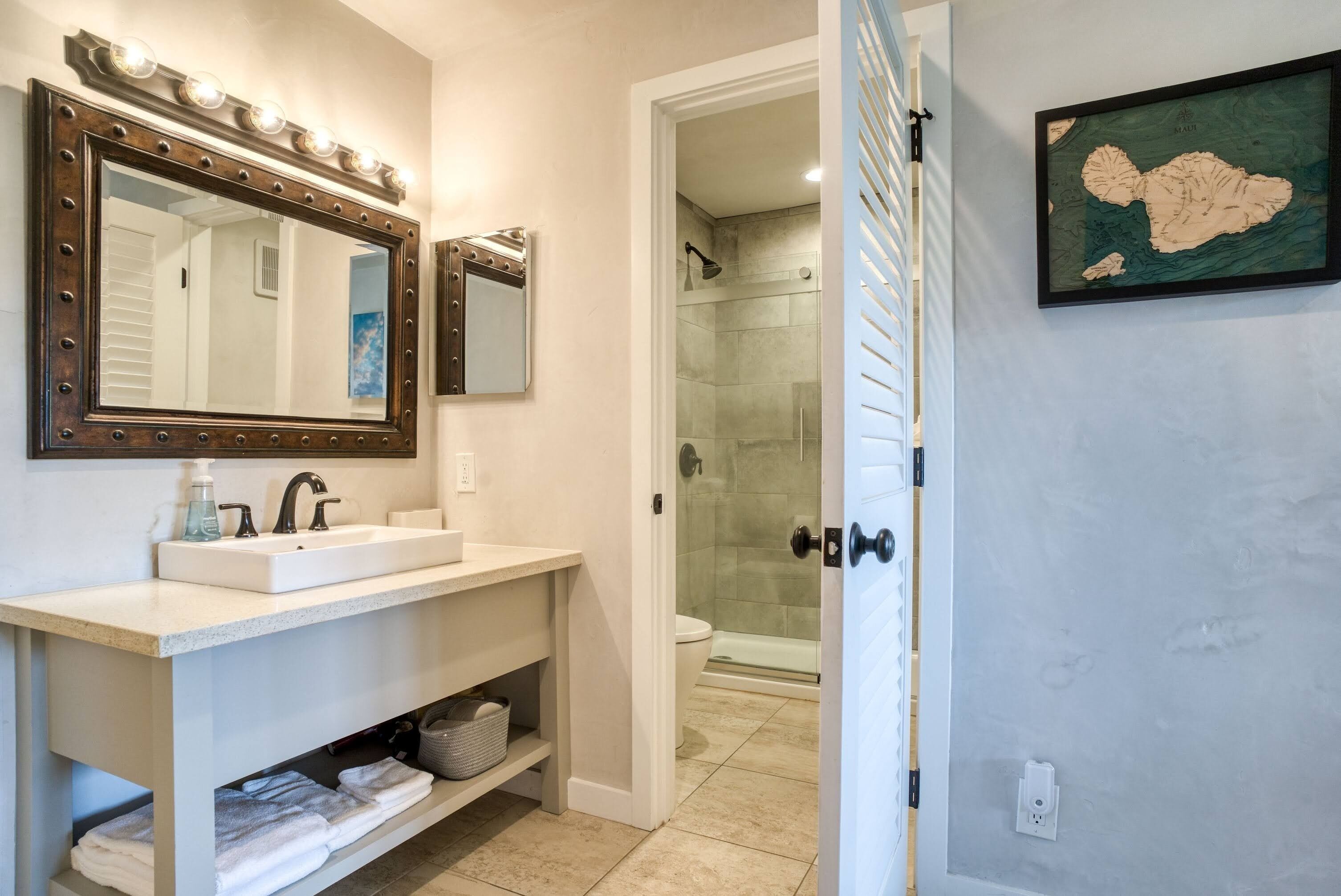 Un baño con tocador, dos espejos, lavabo y zona de ducha.