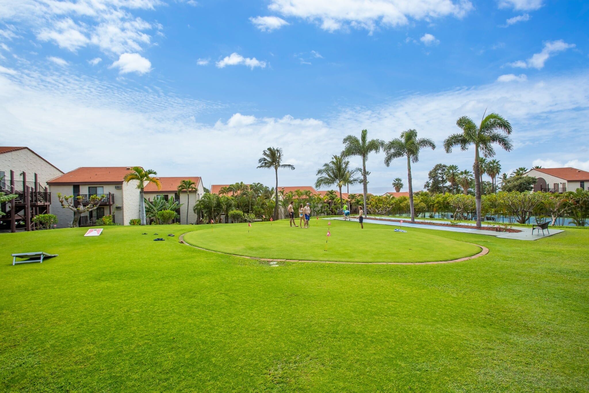 A well-maintained golf course with a clear sky, palm trees, and a pool area.