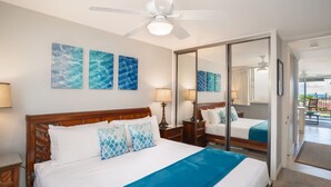 A hotel room with a large bed, a ceiling fan, and artwork on the wall.