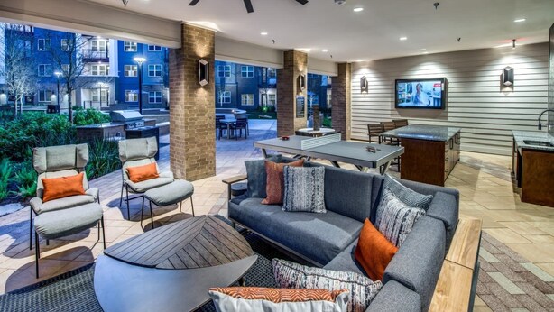 Un espace extérieur aménagé en patio, avec des sièges, un ventilateur de plafond et un écran de télévision.
