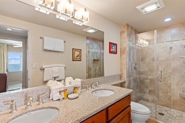 A bathroom with two sinks, a large mirror, and a glass-enclosed shower. - Royal Mauian, #317 2 Bedroom Condo by RedAwning (Kihei)