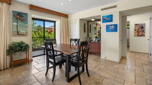 A dining area with a wooden table and chairs, a view of the outdoors through a glass door, and artwork on the walls. - Wailea Elua, #1601 1 Bedroom Condo by RedAwning (Kihei)