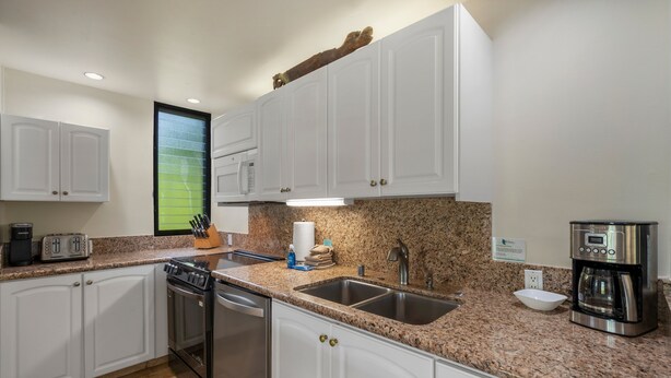 A modern kitchen with white cabinets, granite countertops, stainless steel appliances, and a built-in dishwasher. - Wailea Elua, #1601 1 Bedroom Condo by RedAwning (Kihei)