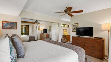 A bedroom with a large bed, a ceiling fan, a TV, and a dresser.